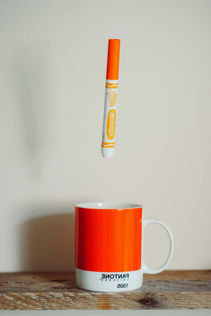 coffee cup orange Crayola crayon pen above mug pantone